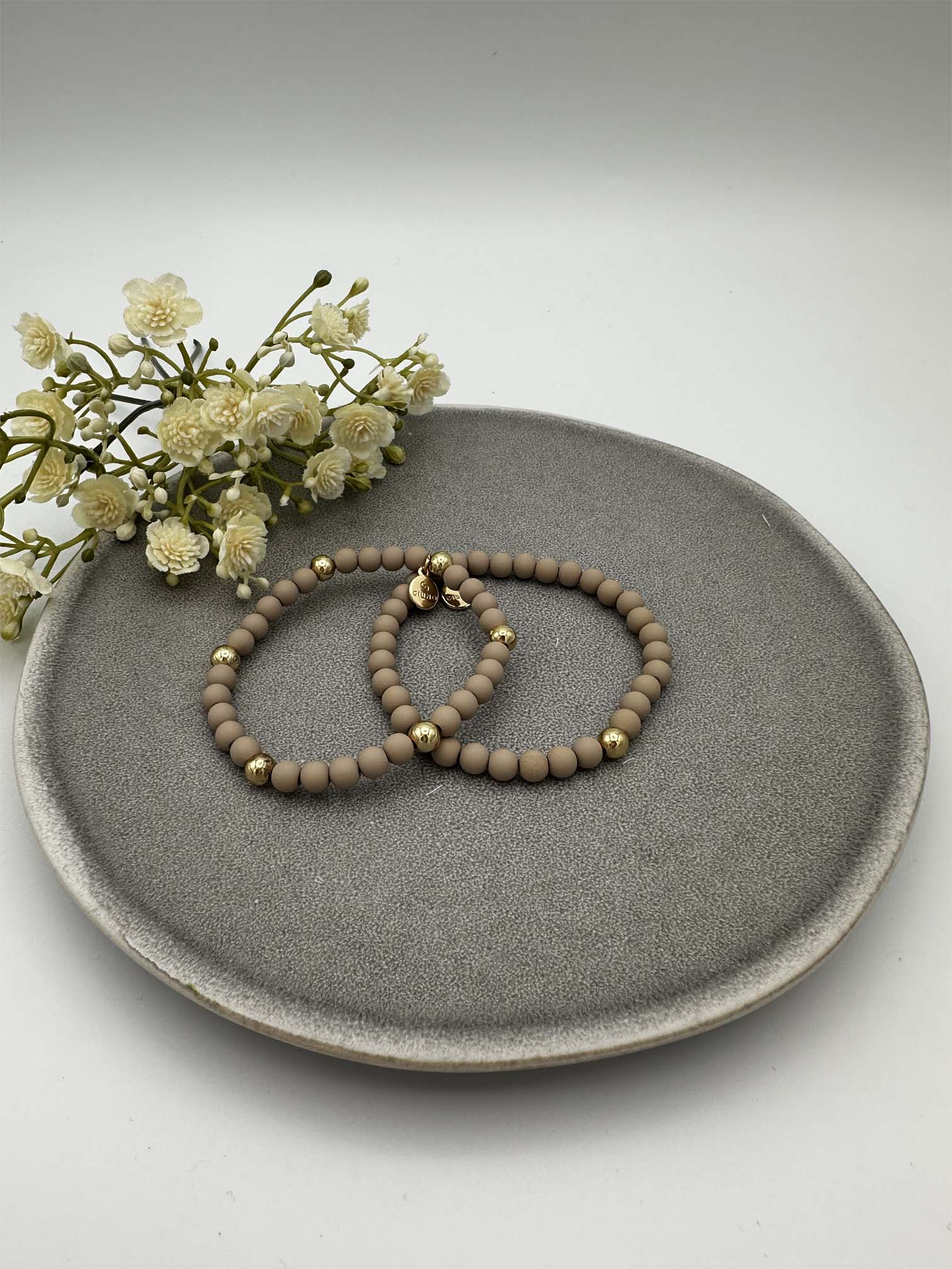 Zwei elastische beige Perlenarmbaender mit goldfarbenen Akzenten