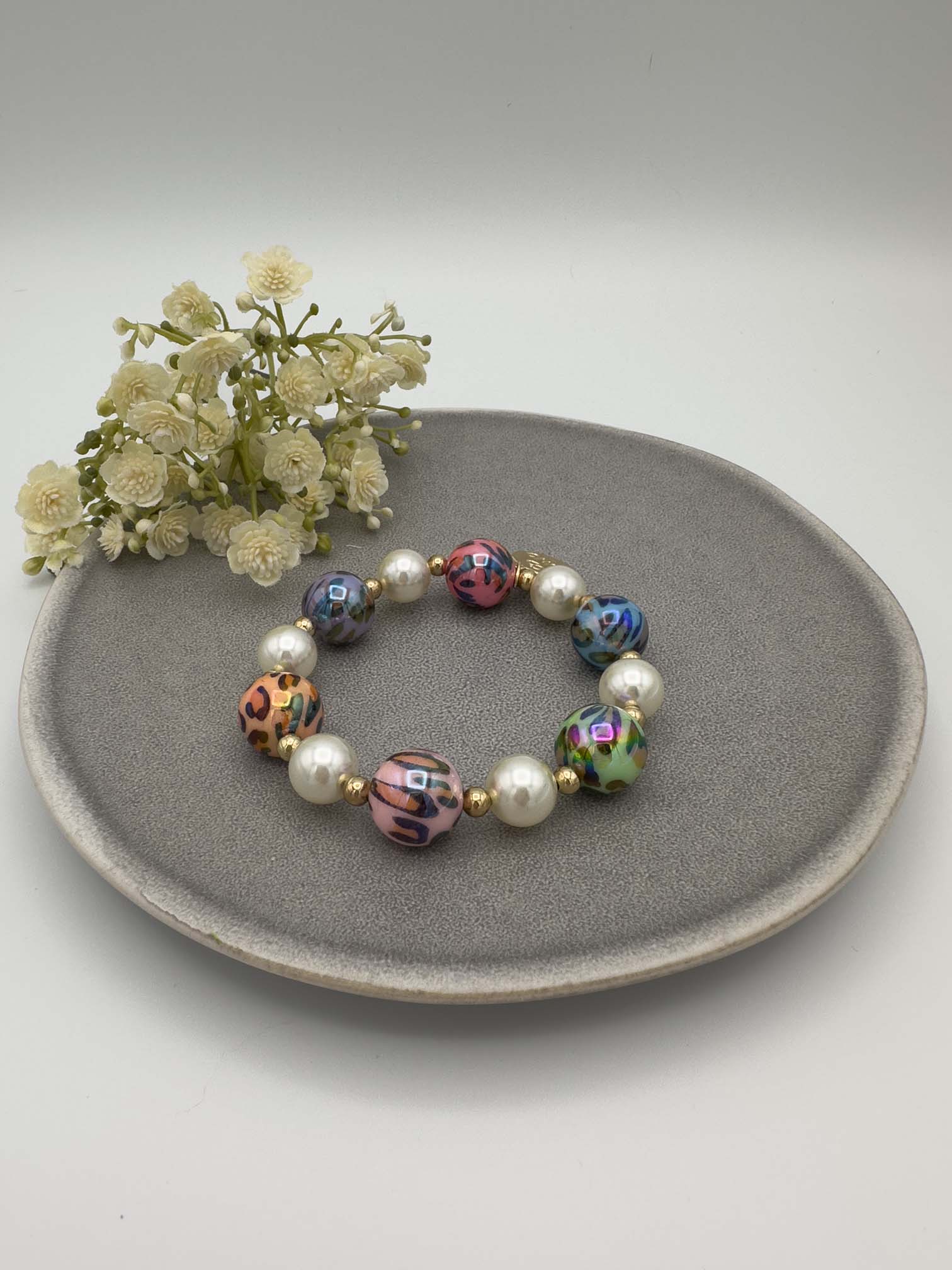 Elastisches Perlenarmband mit bunten marmorierten Kugeln, weißen Perlen und goldfarbenen Zwischenelementen