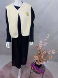 Cremefarbene Teddy-Weste mit flauschiger Oberflaeche, Druckknoepfen und Smiley-Patch auf der Brust.