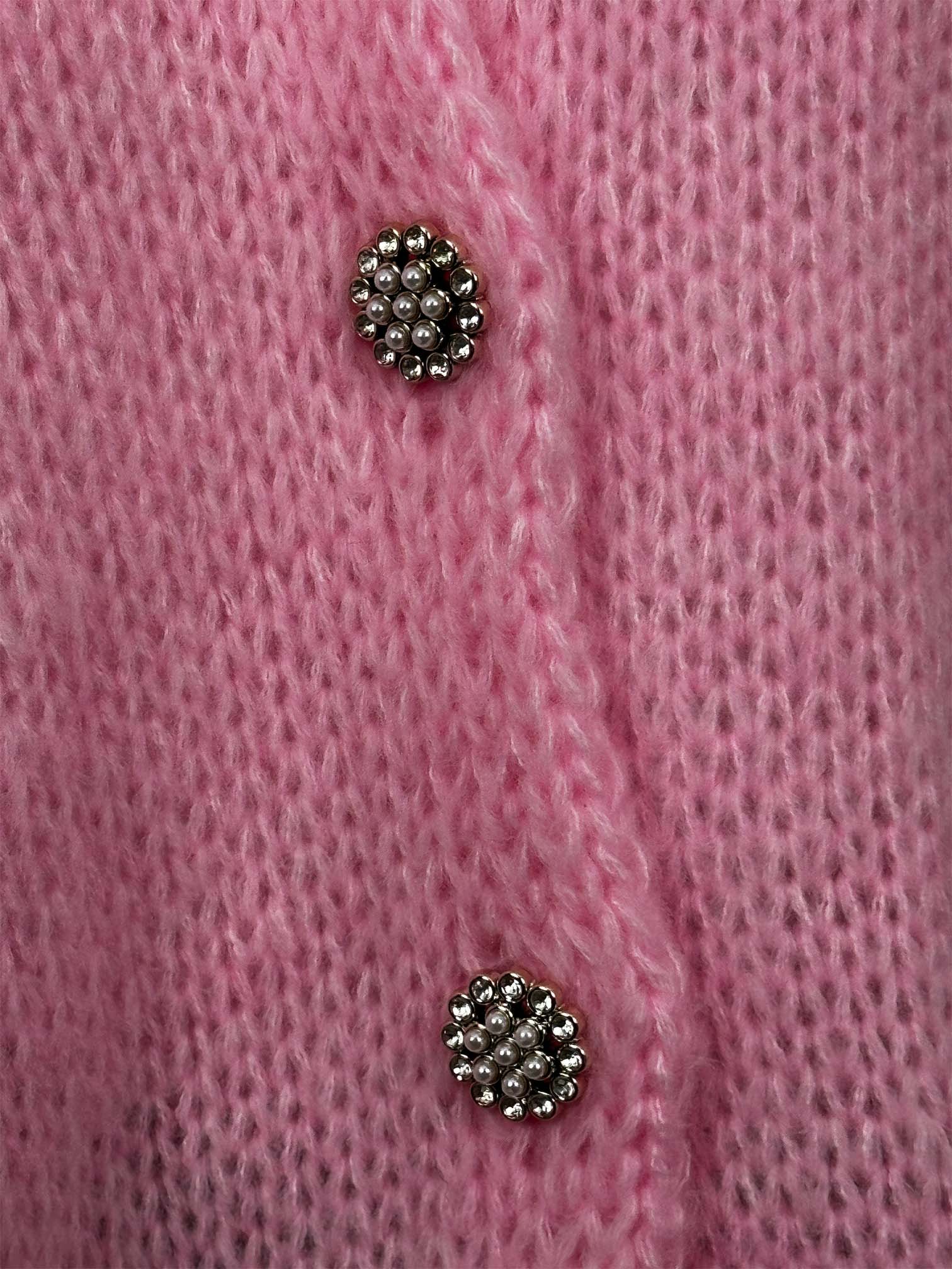 Detailaufnahme von funkelnden Schmuckknöpfen auf rosa Strickjacke