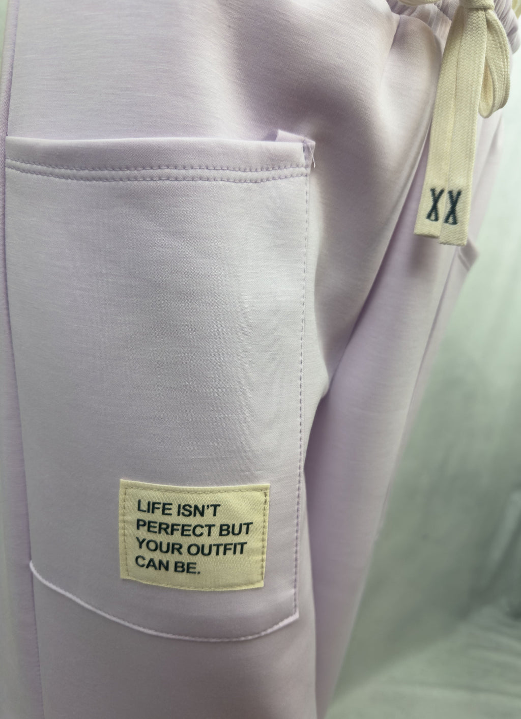 Fliederfarbene Sweathose mit grosser aufgesetzter Tasche, hellem Patch mit dem Text Life isnt perfect but your outfit can be und elastischem Bund mit Kordel