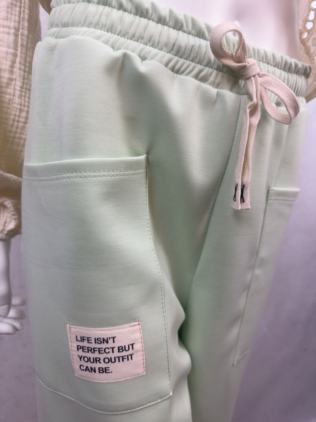 Mintfarbene Sweathose mit aufgesetzter Fronttasche, hellem Stoffpatch mit Schriftzug Life isnt perfect but your outfit can be und elastischem Bund mit Kordel