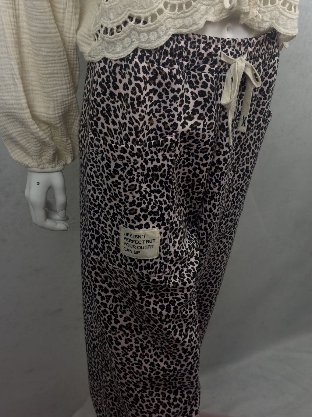 Rosa Leo Hose mit schwarzem und braunem Leo Muster, grosser aufgesetzter Tasche und hellem Stoffpatch mit dem Schriftzug Life isnt perfect but your outfit can be sowie elastischem Bund mit Kordel