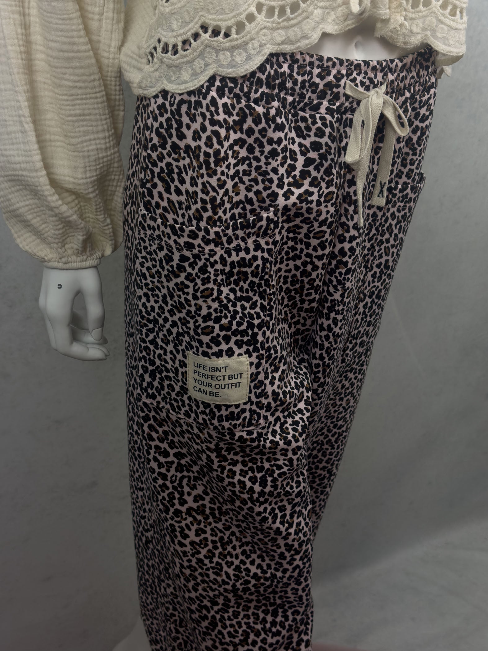 Rosa Leo Hose mit schwarzem und braunem Leo Muster, grosser aufgesetzter Tasche und hellem Stoffpatch mit dem Schriftzug Life isnt perfect but your outfit can be sowie elastischem Bund mit Kordel