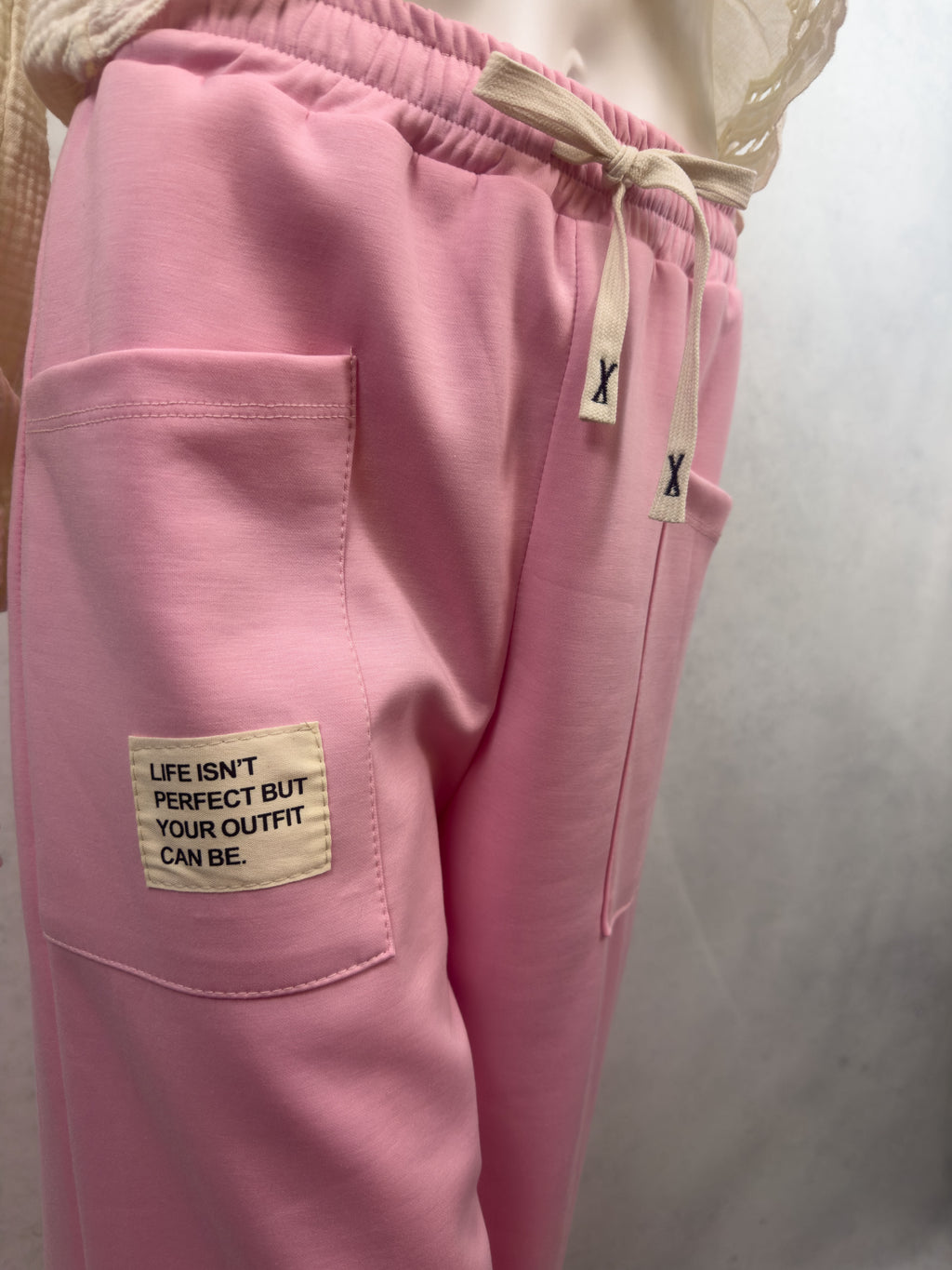 Rosa Sweathose mit aufgesetzter Fronttasche, hellem Stoffpatch mit dem Schriftzug Life isnt perfect but your outfit can be und elastischem Bund mit Kordel