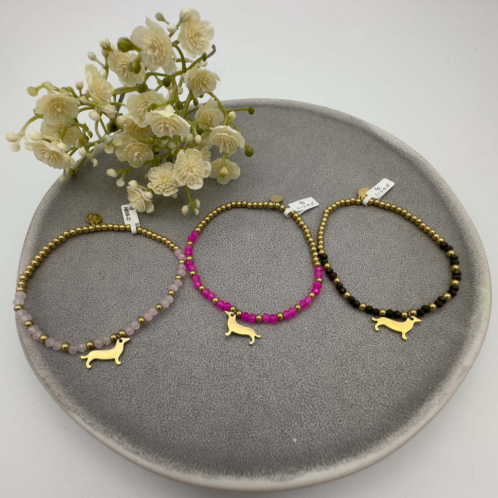 Drei Perlenarmbaender mit goldfarbenem Dackel Anhaenger in Rosa, Pink und Schwarz.