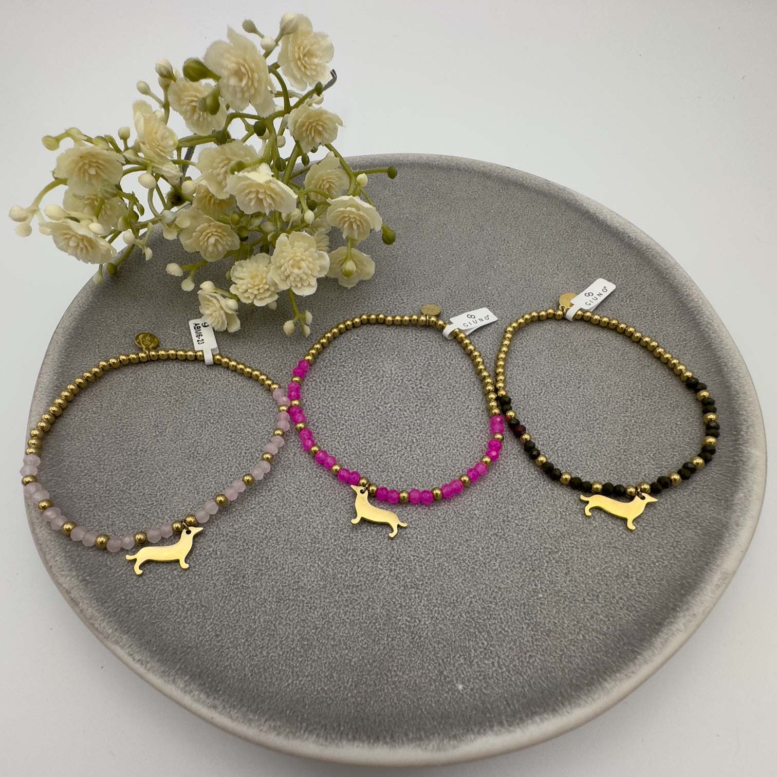 Drei Perlenarmbaender mit goldfarbenem Dackel Anhaenger in Rosa, Pink und Schwarz.
