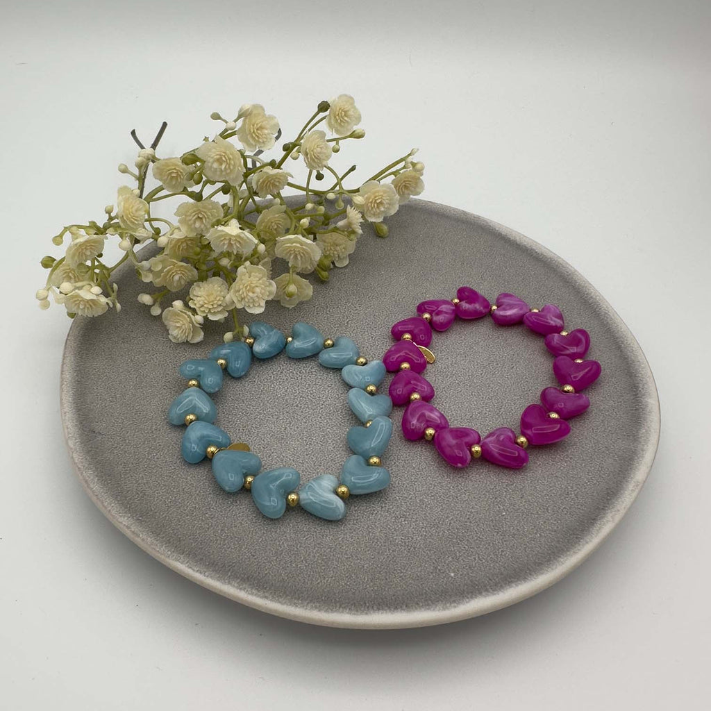 Elastisches Armband mit herzfoermigen Perlen in Hellblau und Pink und goldfarbenen Kugeln