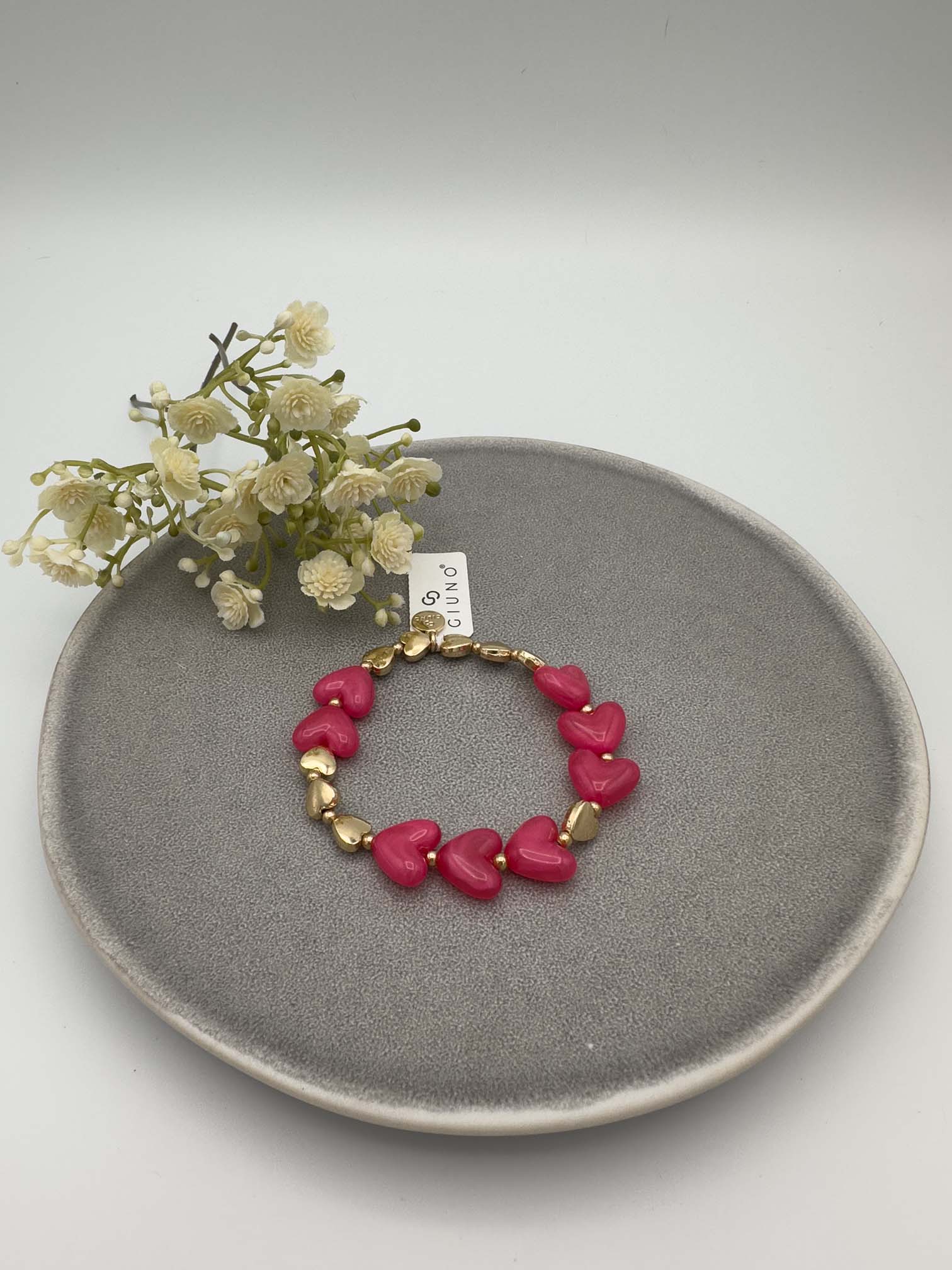 Pinkfarbenes Armband mit Herzperlen und goldfarbenen Details.