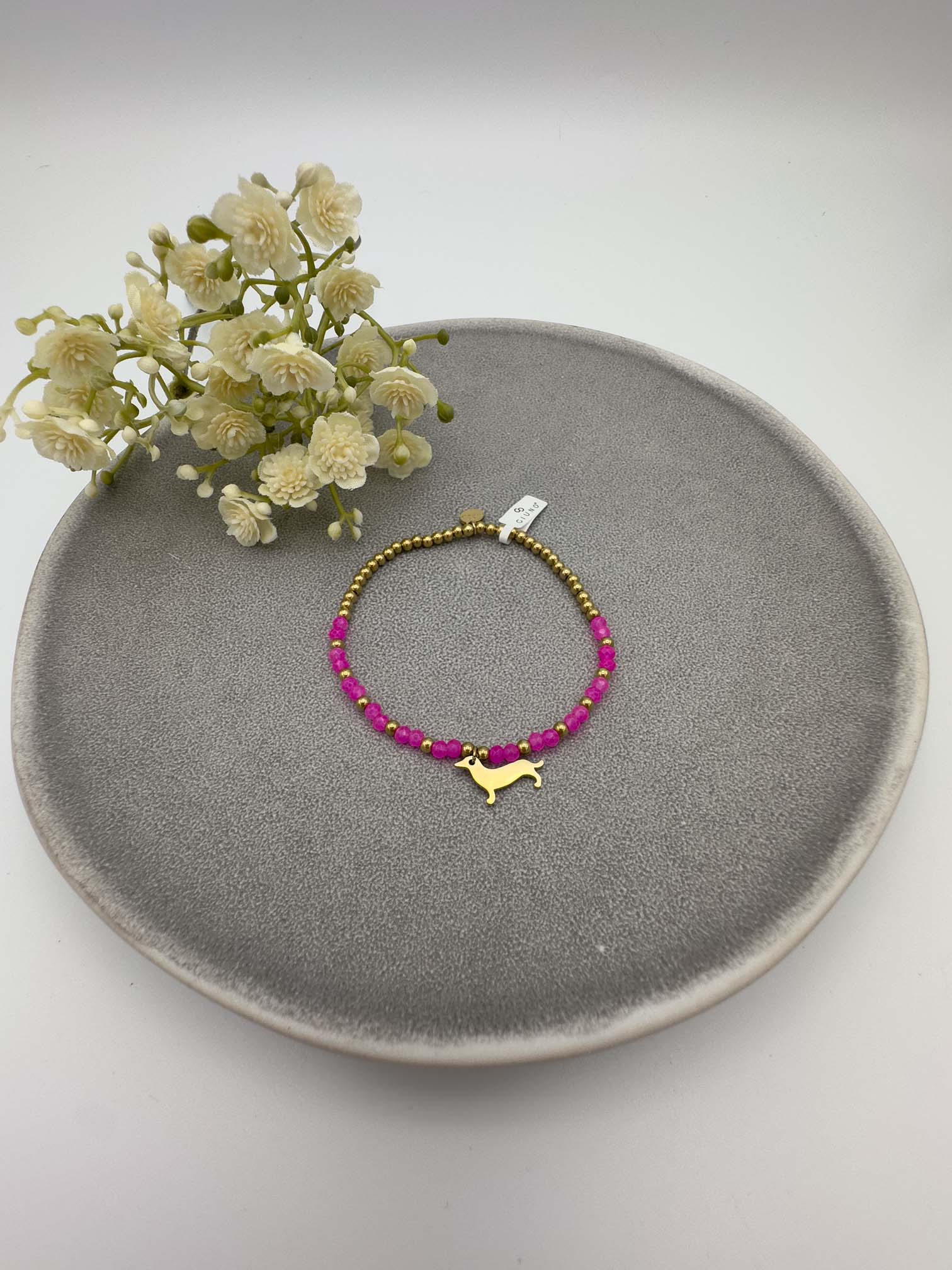 Pinkes Perlenarmband mit goldfarbenem Dackel Anhaenger.