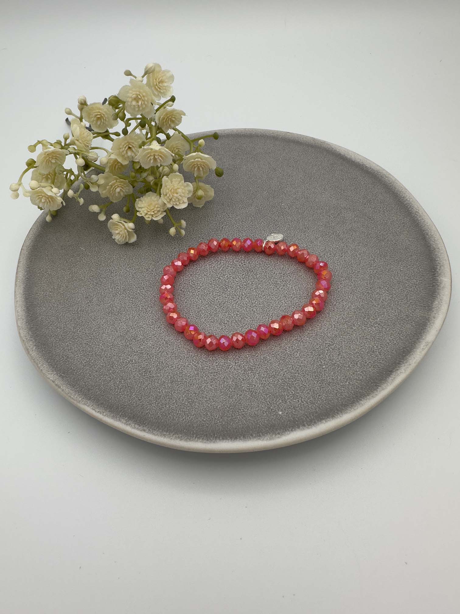 Elastisches Perlenarmband mit rot schimmernden facettierten Perlen.