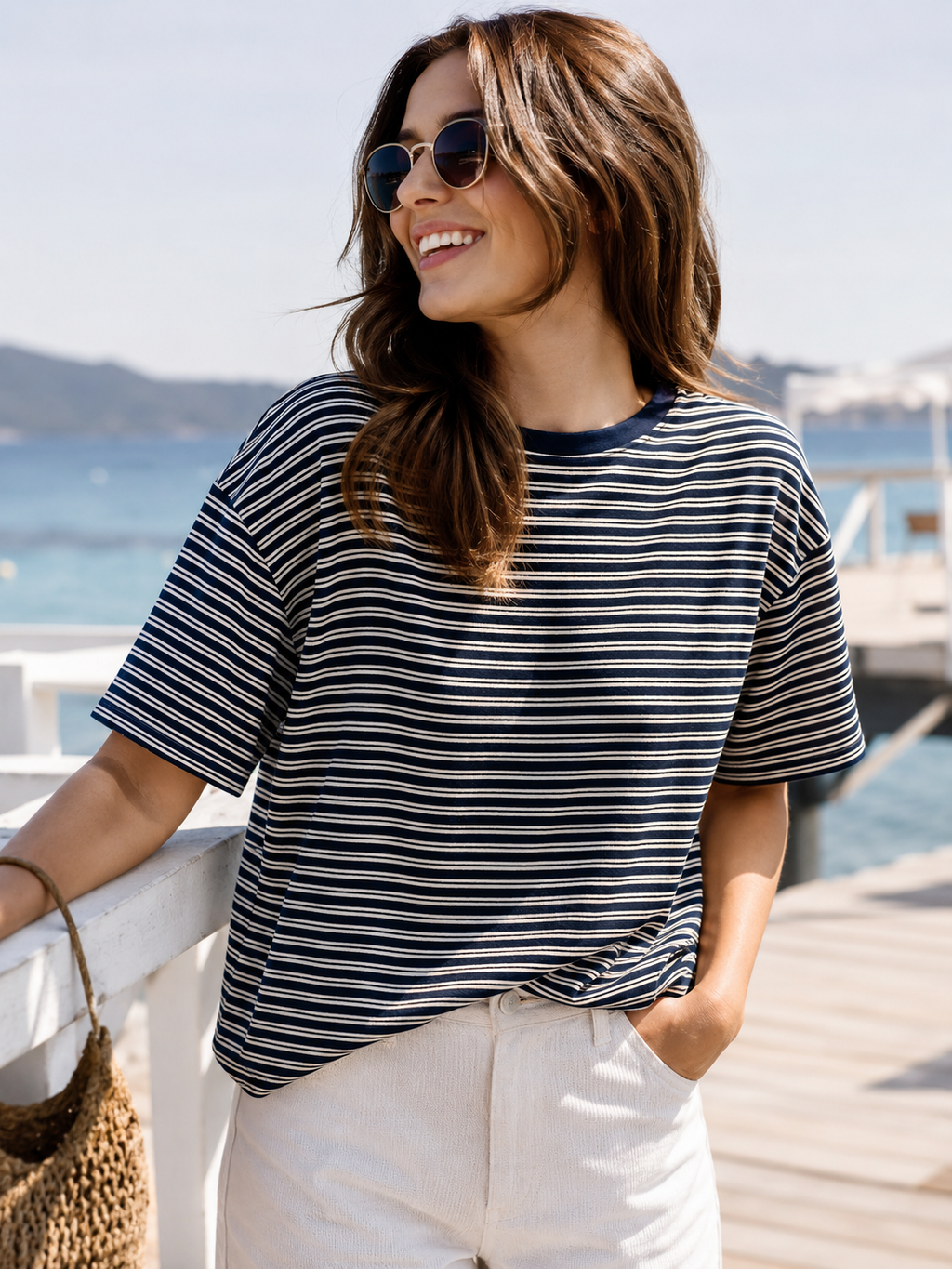 Frau trägt navy creme gestreiftes Oversize Shirt mit heller Hose am Meer