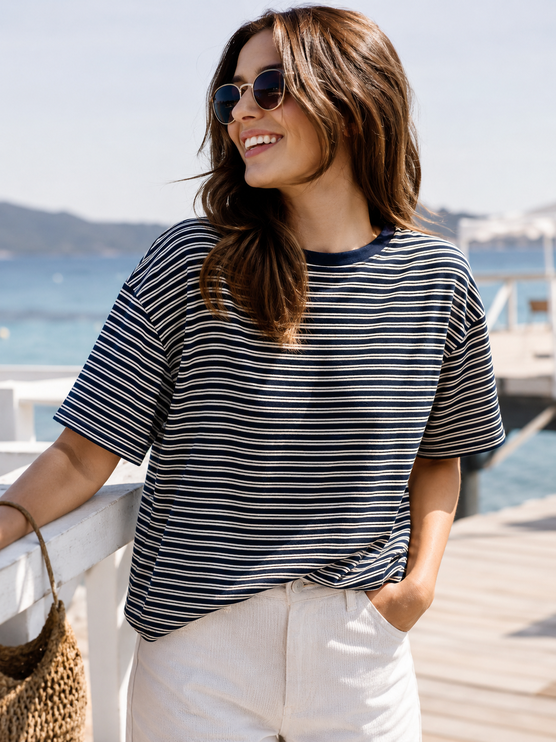 Frau trägt navy creme gestreiftes Oversize Shirt mit heller Hose am Meer