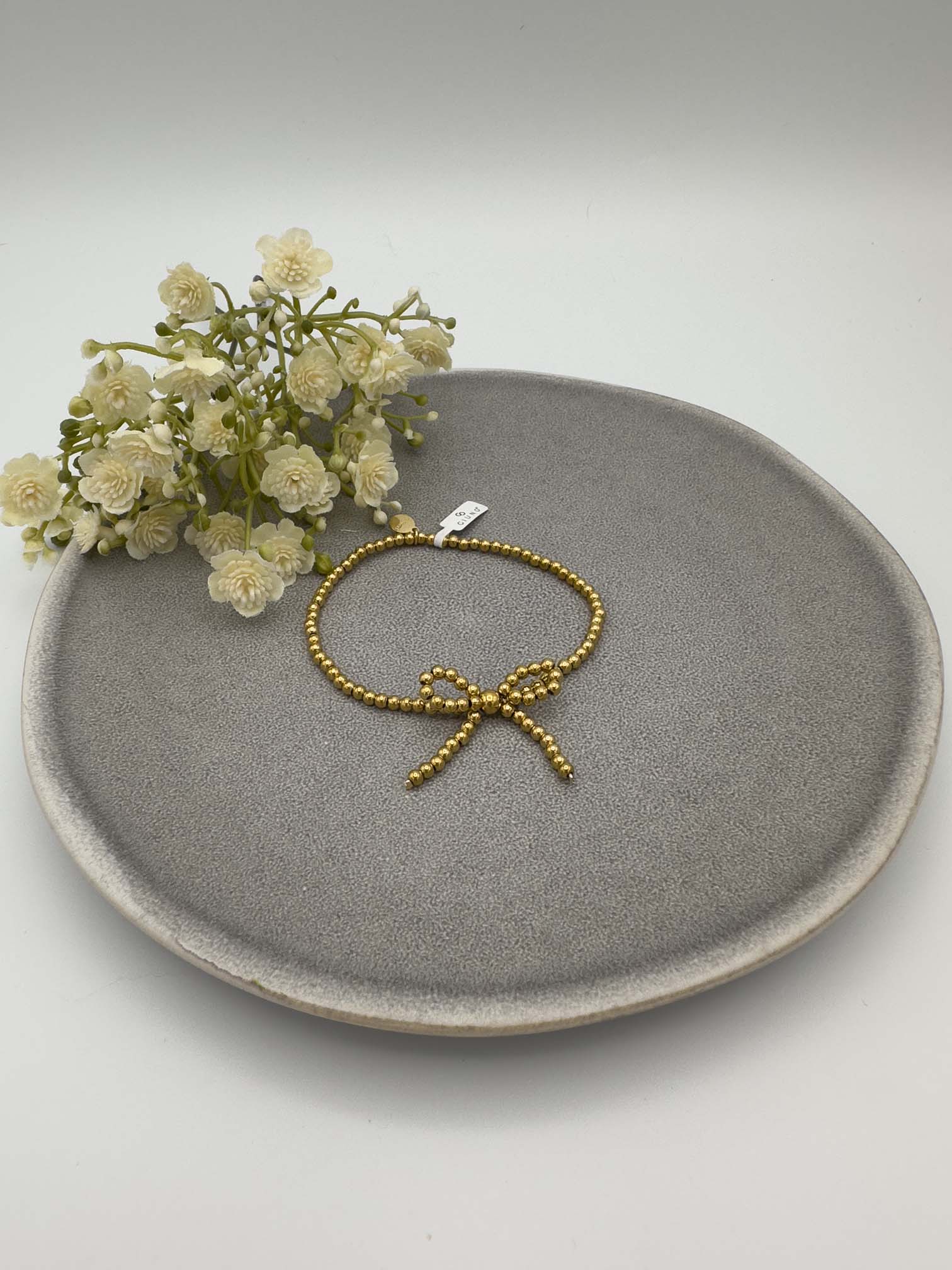 Elastisches Armband aus goldfarbenen Perlen mit dekorativer Schleife