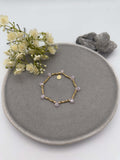 Elastisches goldfarbenes Perlenarmband mit kleinen Metallperlen und gleichmaessig verteilten facettierten rosefarbenen Glasperlen.
