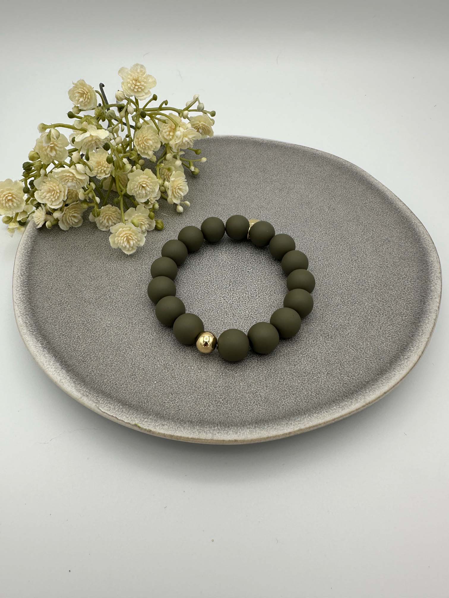 Elastisches Armband mit matten olivgruenen Perlen und einer goldenen Kugel