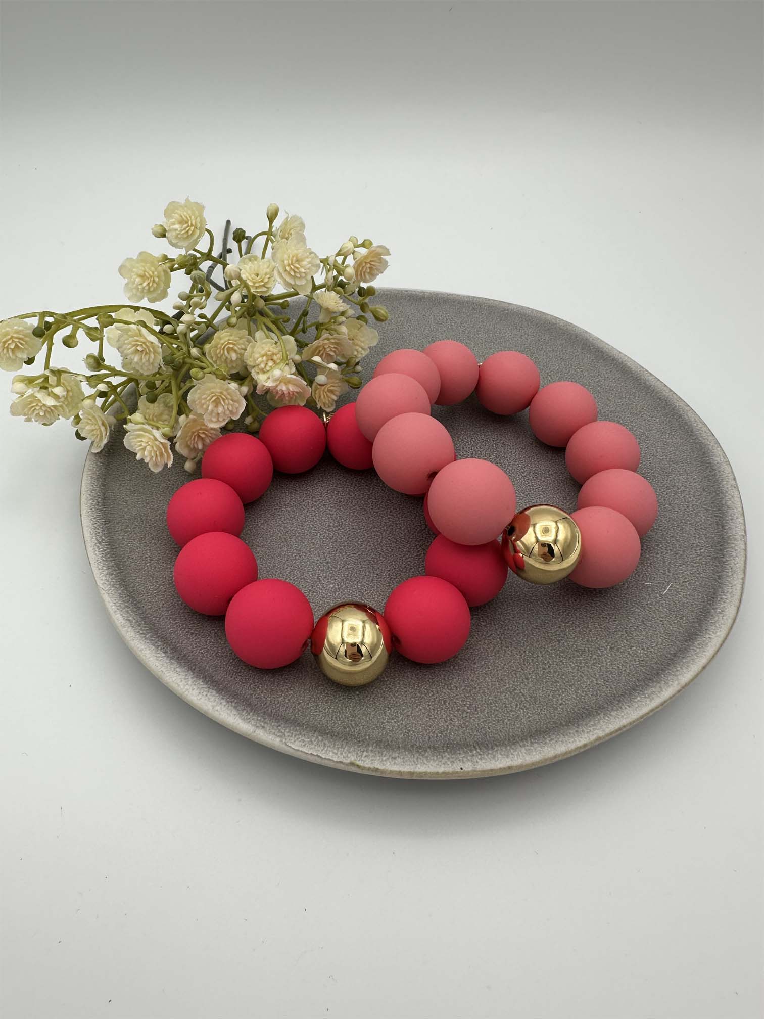 Zwei elastische Perlenarmbaender in Rosa und Pink mit goldfarbenen Kugeln 
