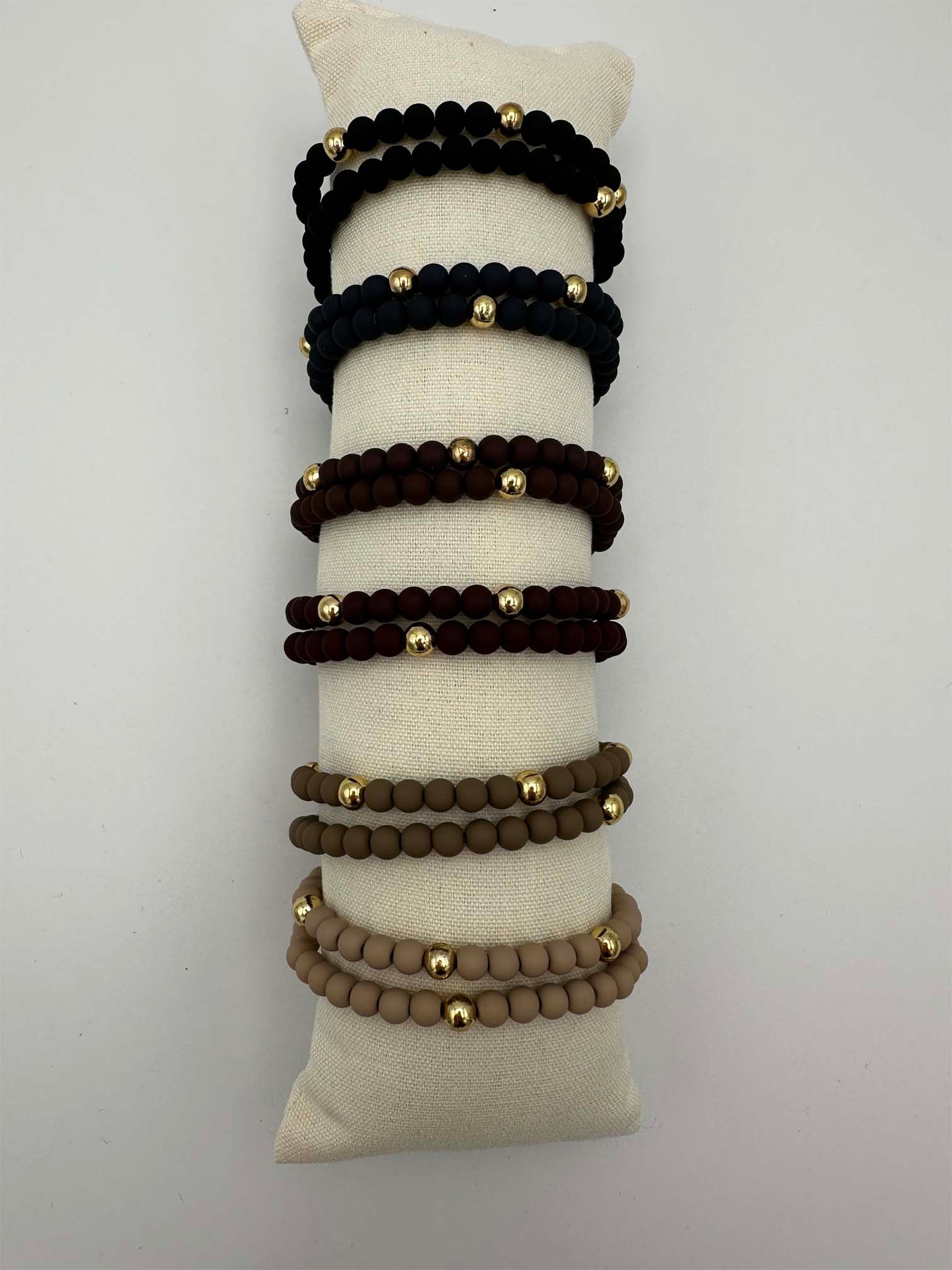 Mehrere elastische Perlenarmbaender in Schwarz, Dunkelblau, Bordeaux, Braun und Beige mit goldfarbenen Akzenten