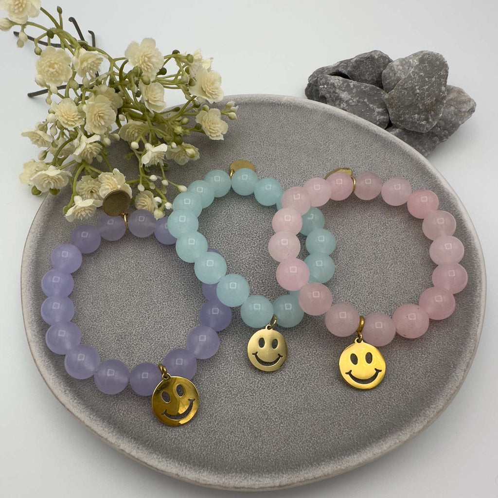 Elastisches Damen Armband mit runden Perlen in Pastellfarben und goldfarbenem Smiley Anhaenger