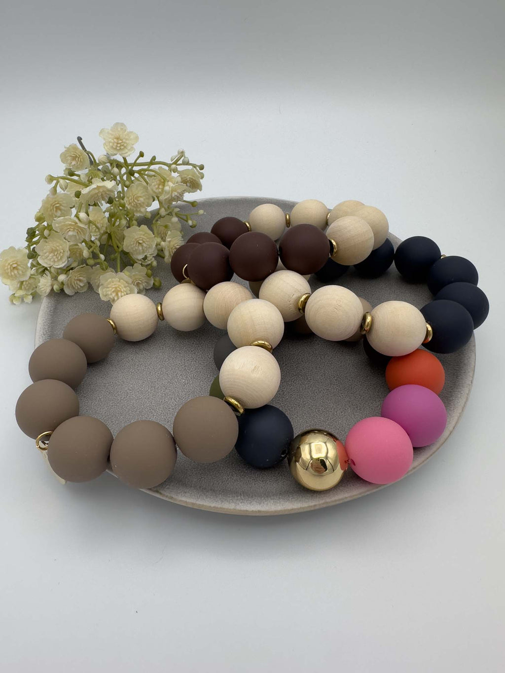 Elastisches Perlenarmband mit Holz und Silikonperlen in Naturtoenen, Dunkelblau, Braun und Pink mit goldenen Zwischenelementen