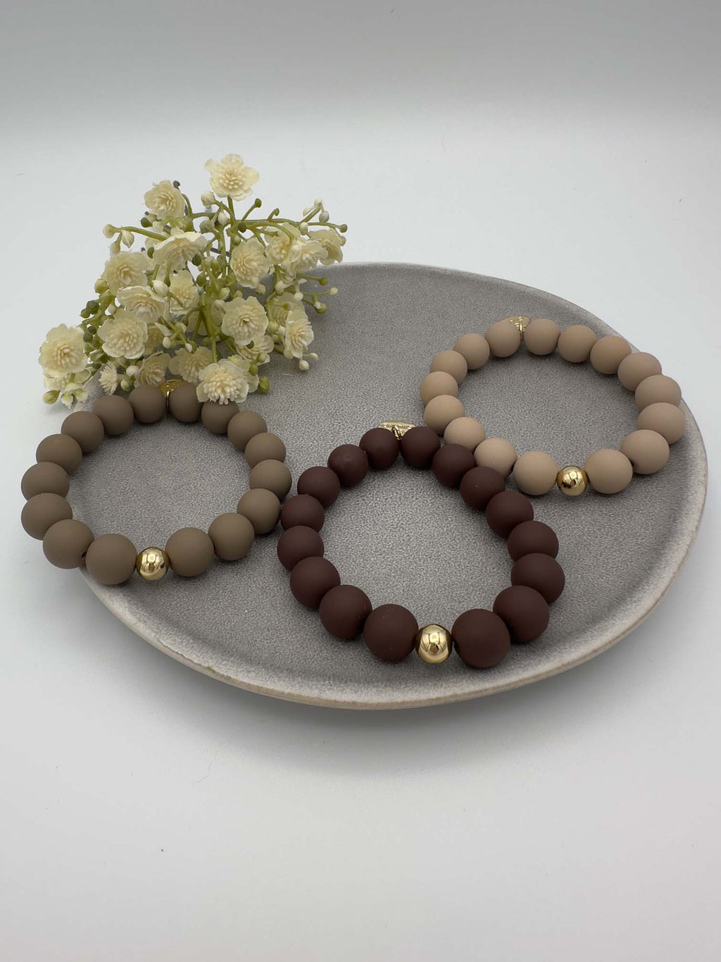 Drei elastische Perlenarmbaender in Taupe, Dunkelbraun und Beige mit jeweils einer goldenen Akzentperle