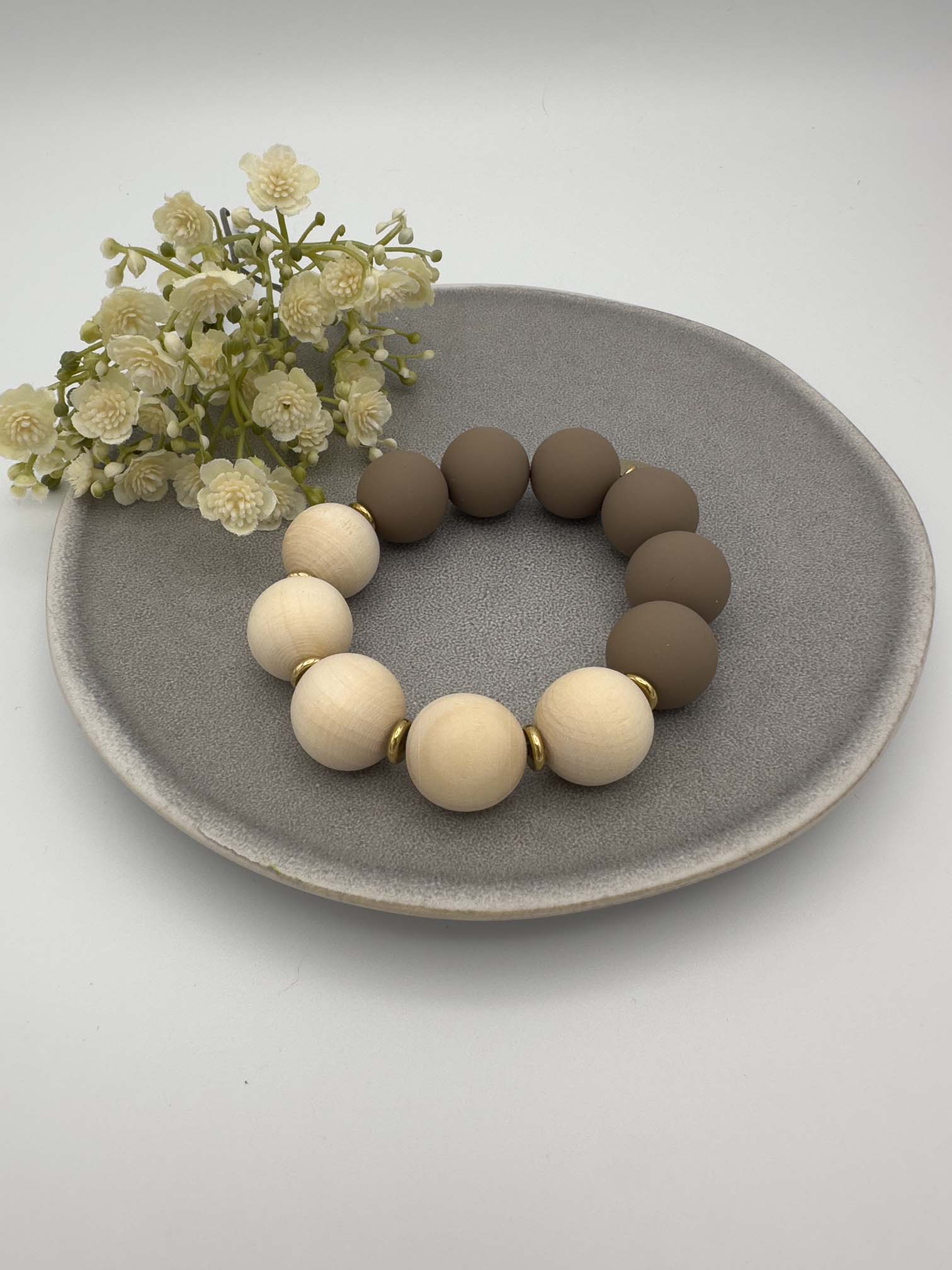 Elastisches Armband mit matten taupefarbenen und natur Holzperlen sowie goldenen Zwischenelementen