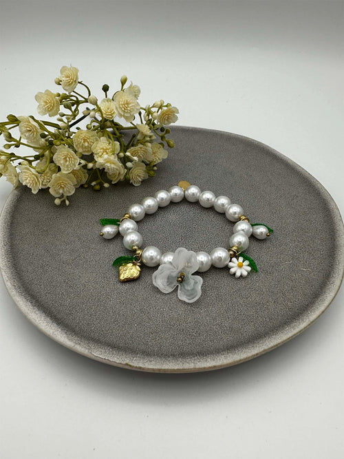 Elastisches Perlenarmband mit weissen Perlen sowie Blumen- und Erdbeeranhaengern