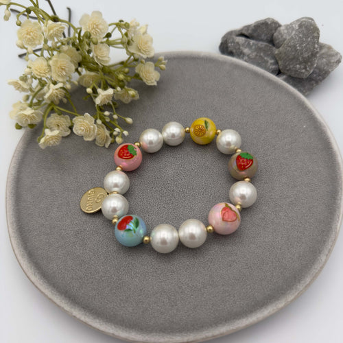 Elastisches Perlenarmband mit weissen Perlen und bunten Fruchtmotiven wie Erdbeere, Zitrone und Pfirsich