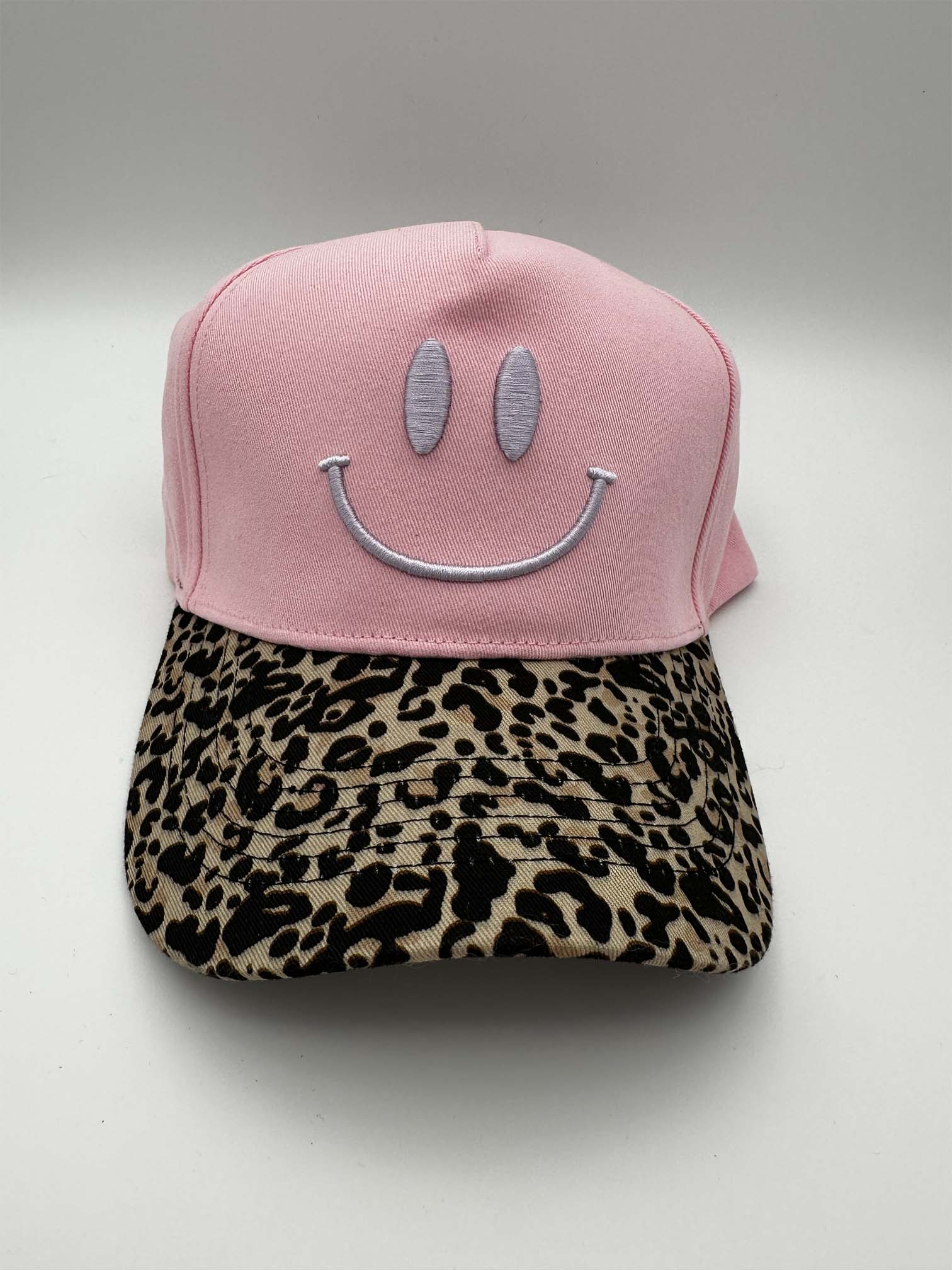 Rosa Baseball Cap mit gesticktem Smiley in Grau auf der Vorderseite und gebogenem Schirm im Leo-Print