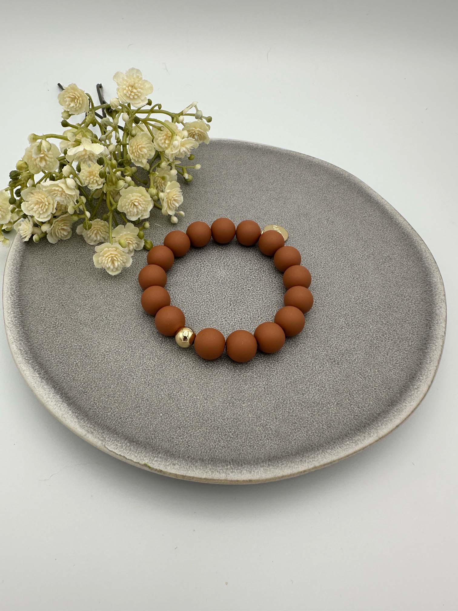 Elastisches Armband mit matten rostorangefarbenen Perlen und einer goldenen Akzentkugel