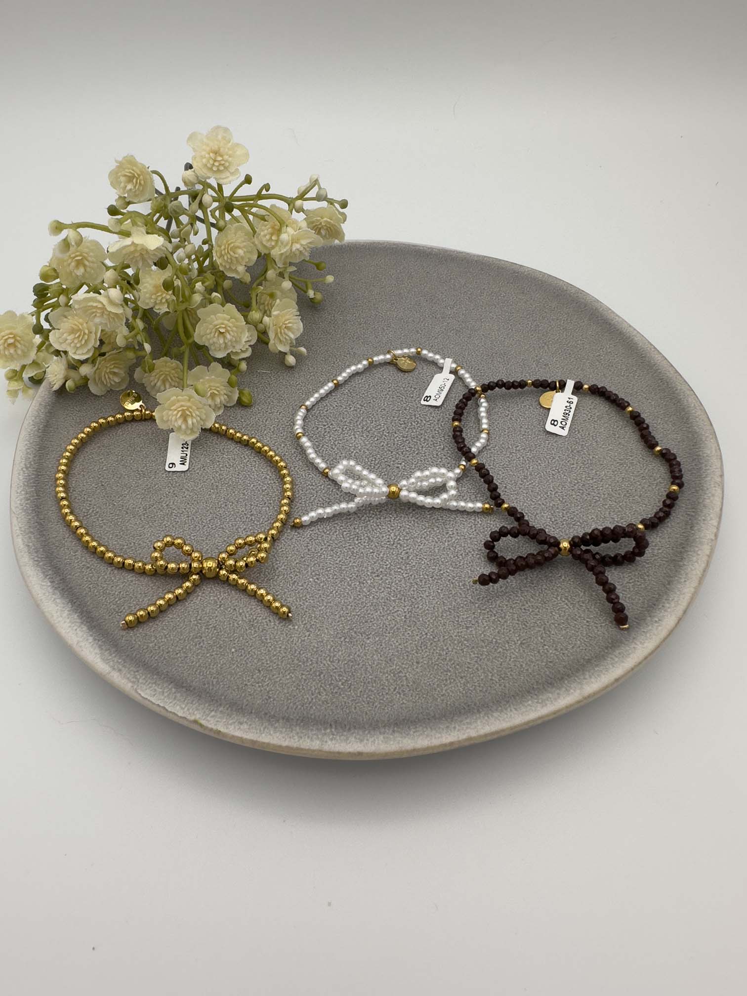 Drei elastische Perlenarmbänder mit Schleifendetail in Gold Weiß und Dunkelbraun