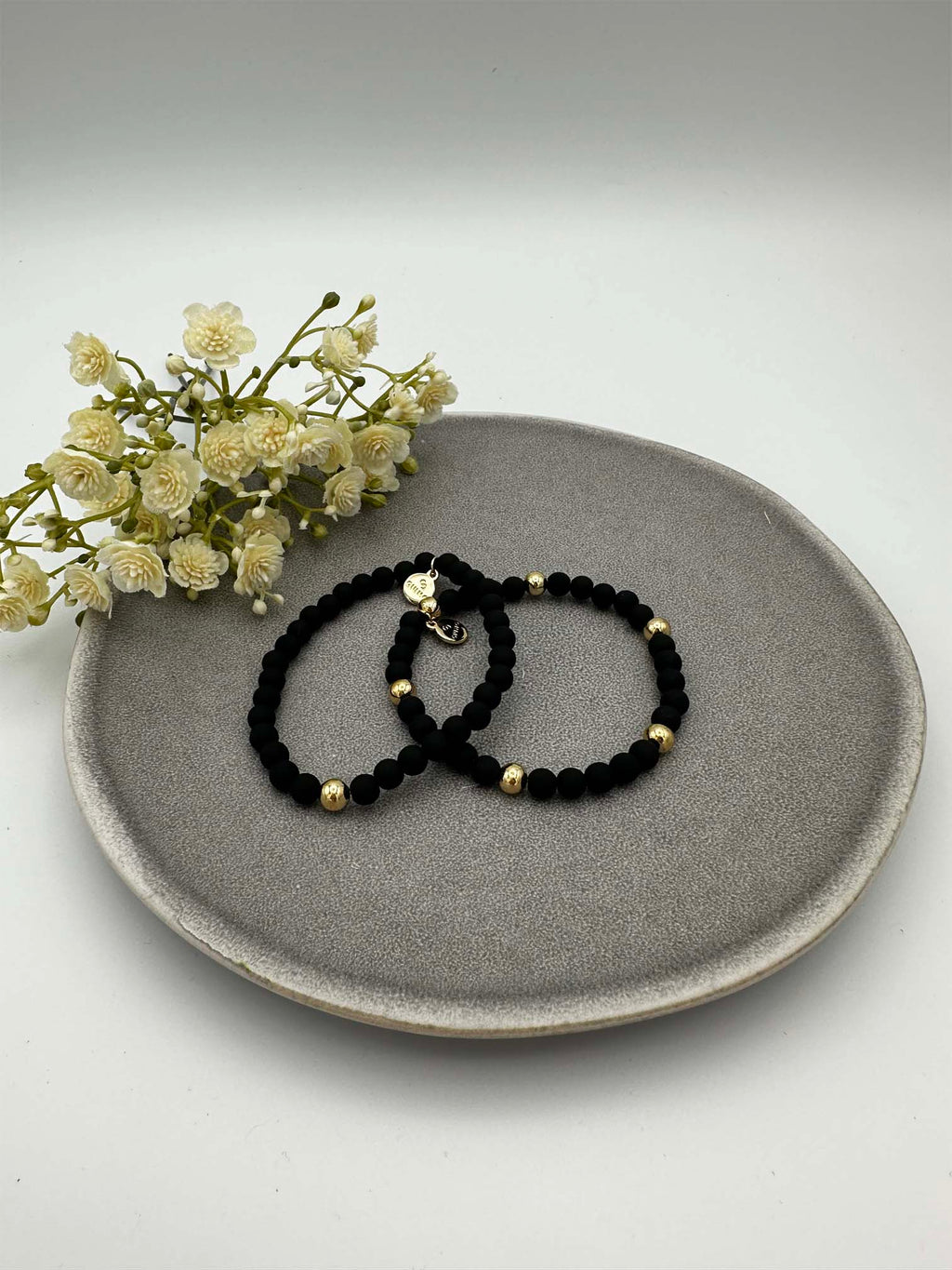 Zwei elastische schwarze Perlenarmbaender mit goldfarbenen Akzenten
