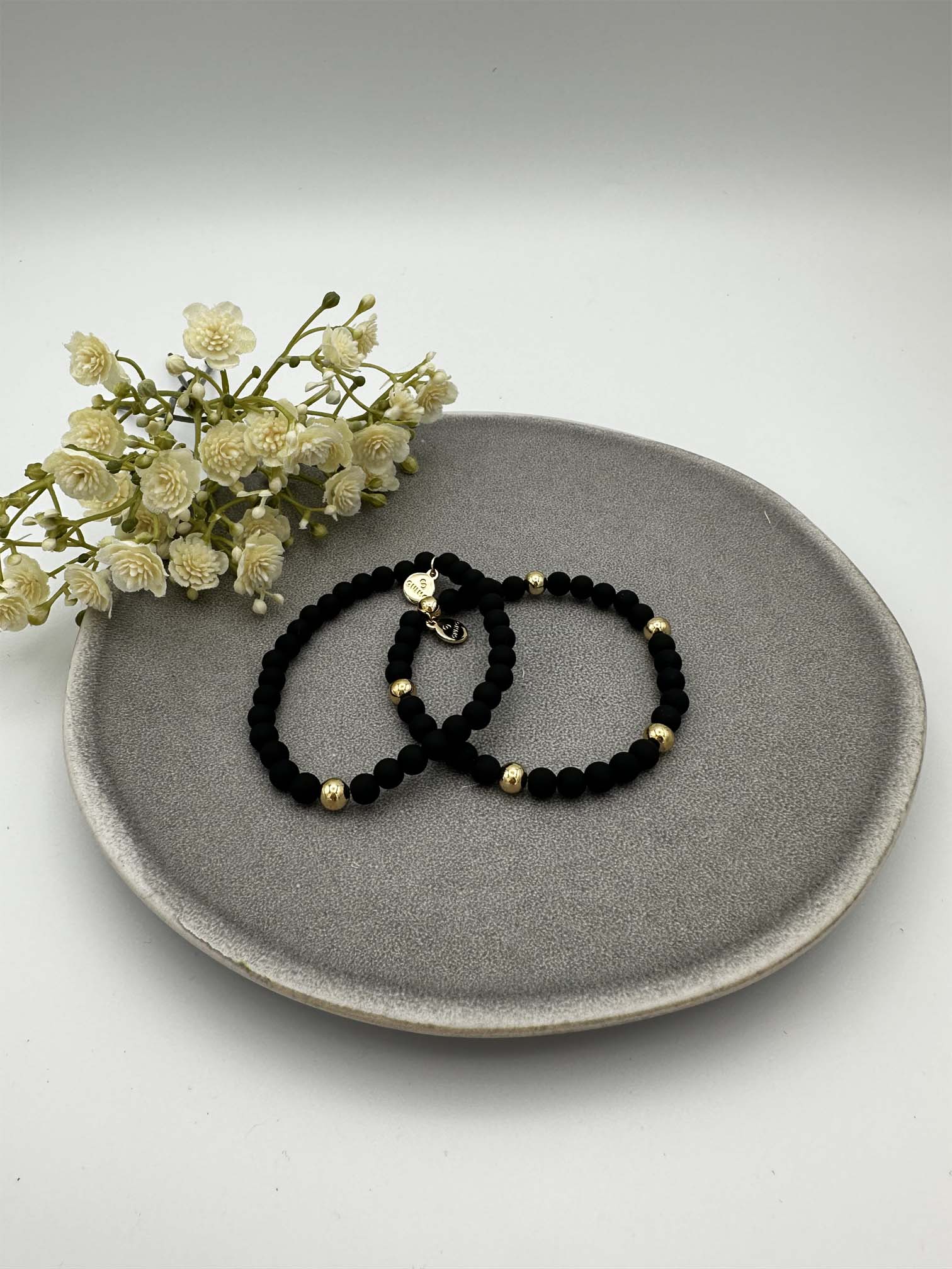 Zwei elastische schwarze Perlenarmbaender mit goldfarbenen Akzenten