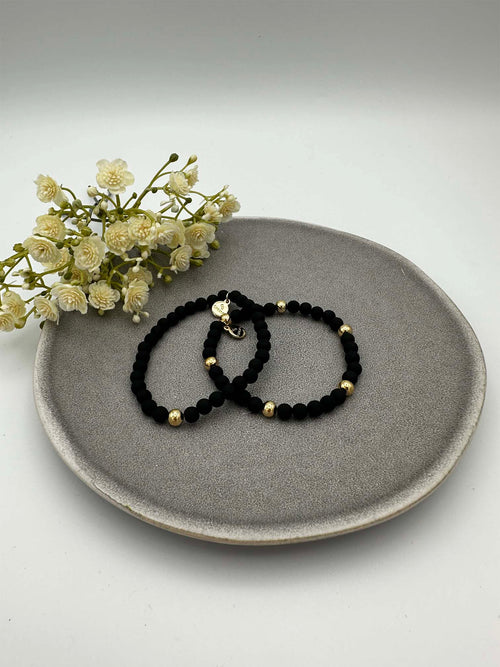 Zwei elastische schwarze Perlenarmbaender mit goldfarbenen Akzenten