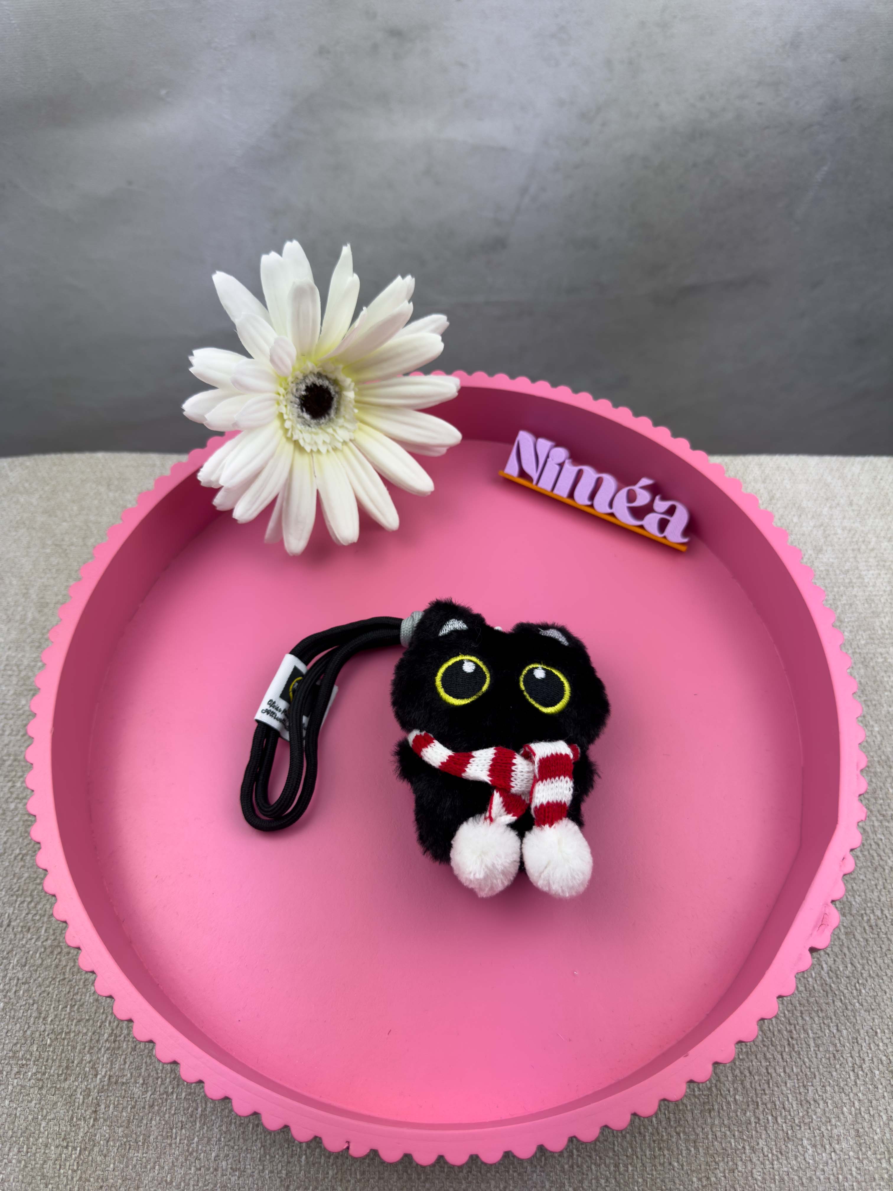 Kleiner schwarzer pluesch Katzen Schluesselanhaenger mit grossen gelben Augen und rotem gestreiftem Schal