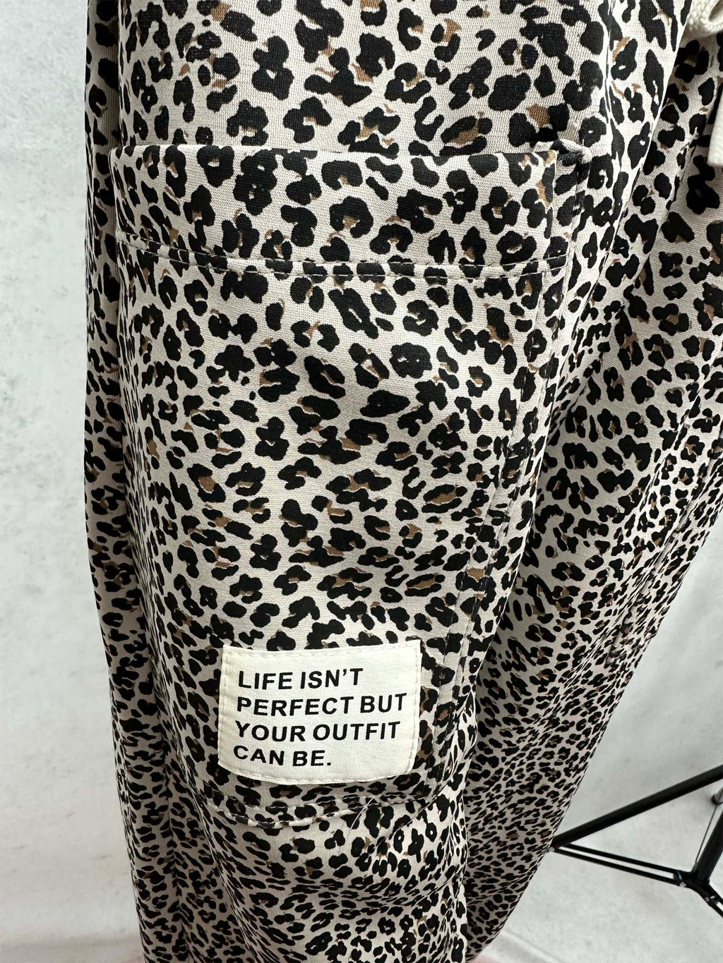 Stoffpatch mit Schriftzug „Life isn’t perfect but your outfit can be“ auf leopardgemustertem Stoff mit aufgenähter Tasche