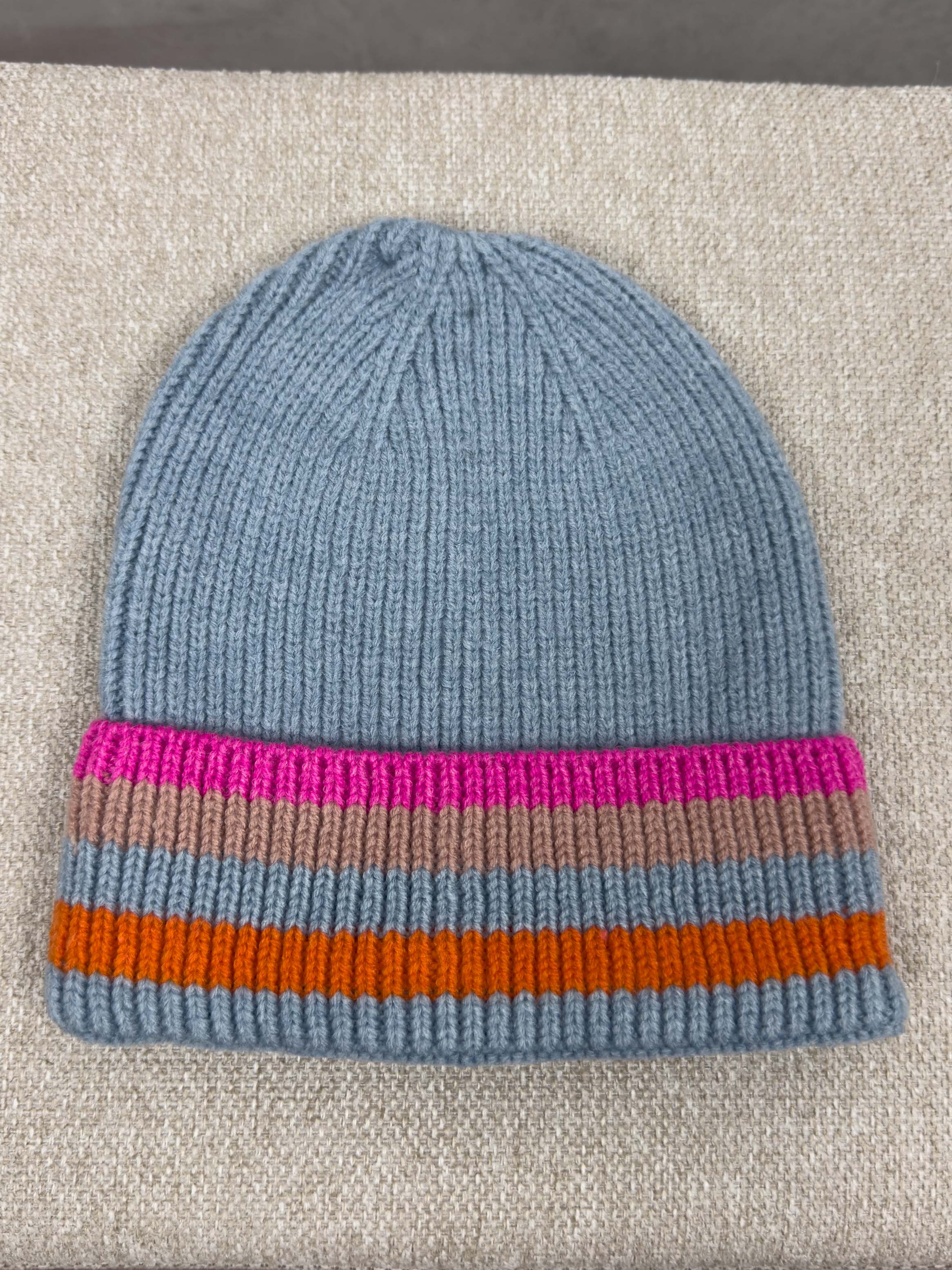 Hellblaue Strickmuetze mit geripptem Muster und breitem Umschlag mit Streifen in Pink, Beige, Orange und Hellblau