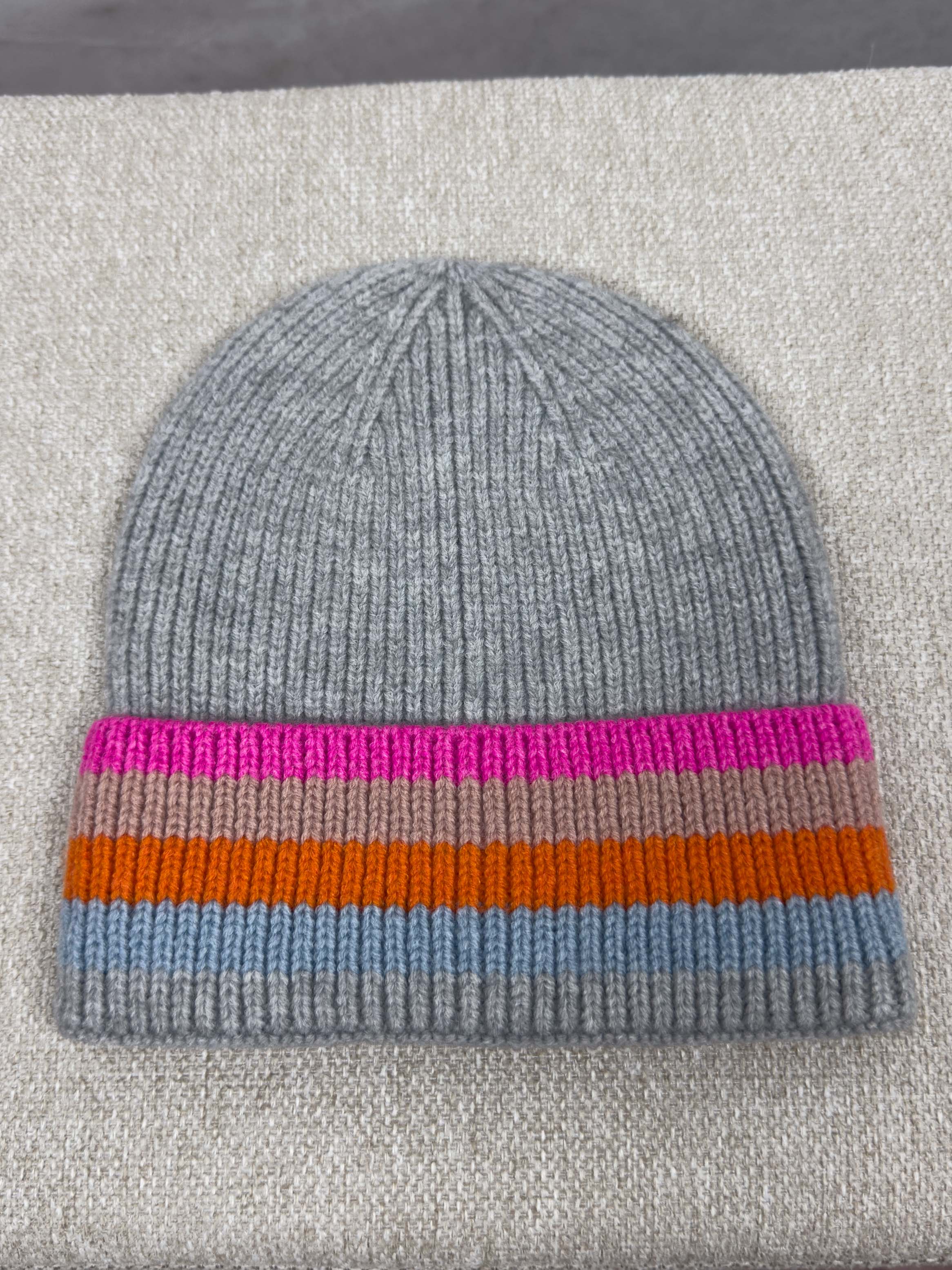 Graue Strickmuetze mit geripptem Muster und breitem Umschlag mit Streifen in Pink, Beige, Orange und Hellblau