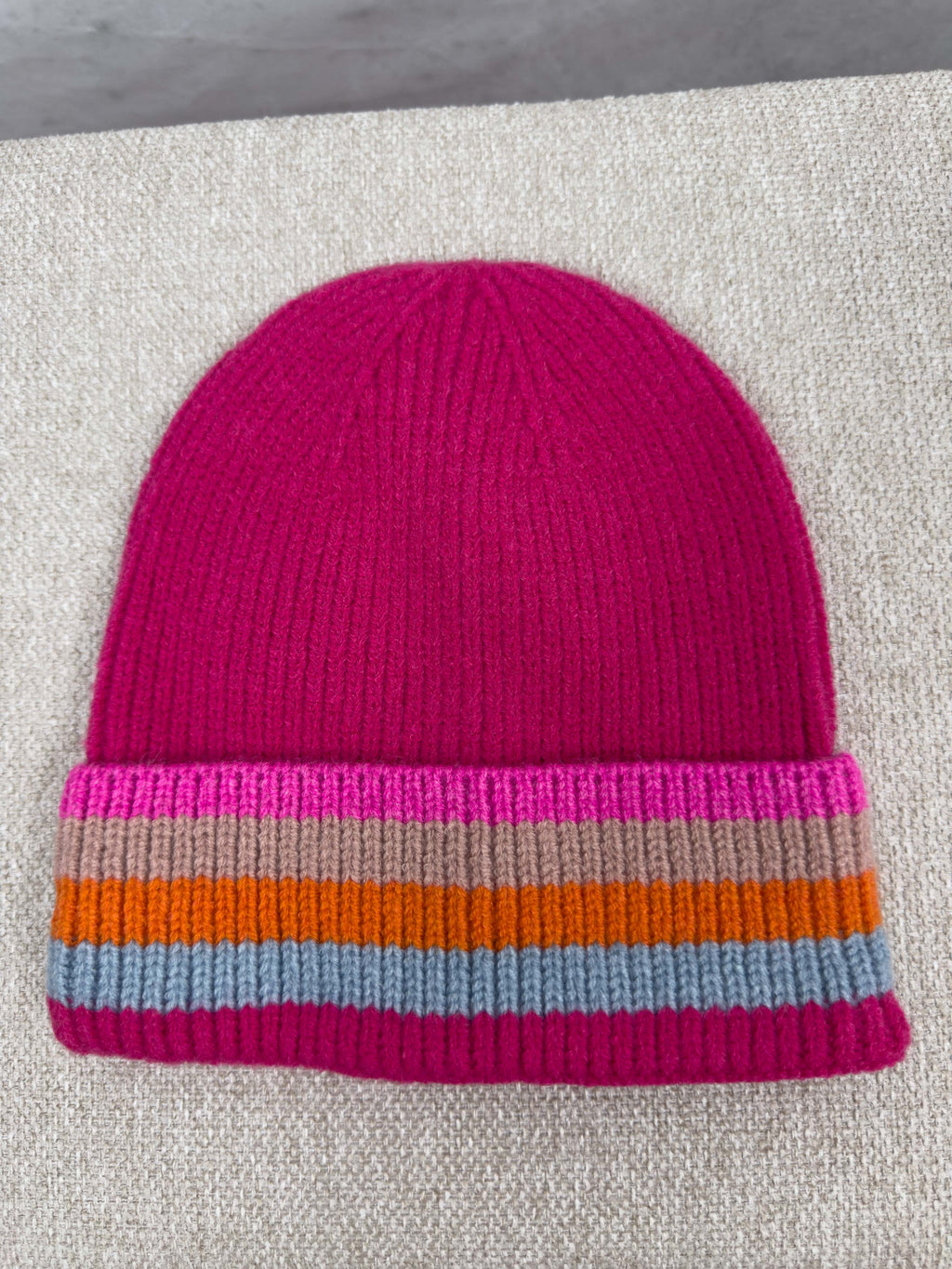 Pinke Strickmuetze mit geripptem Muster und breitem Umschlag mit Streifen in Pink, Beige, Orange und Hellblau