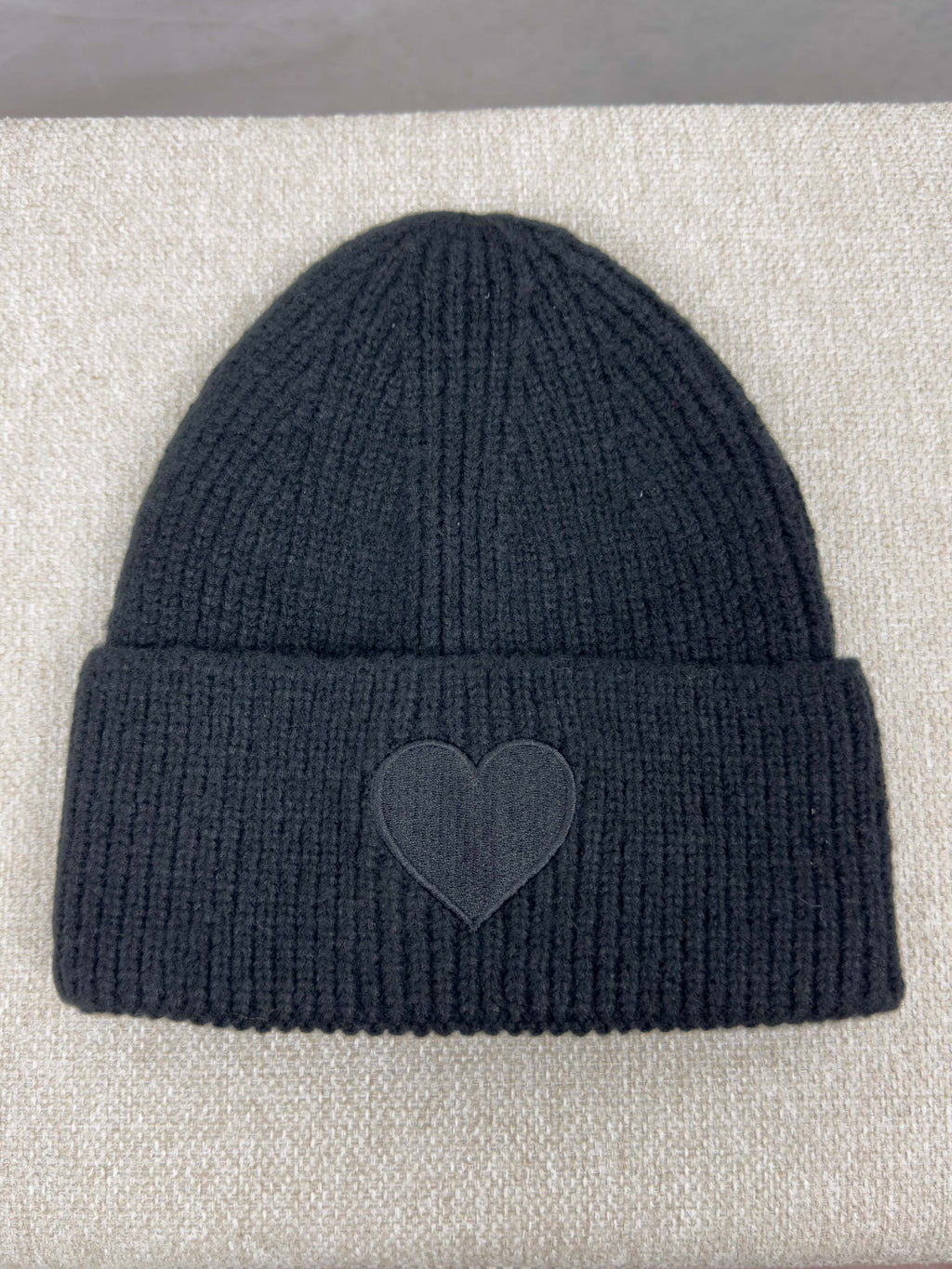 Schwarze gerippte Strickmuetze mit breitem Umschlag und tonaler Herz Applikation auf der Vorderseite