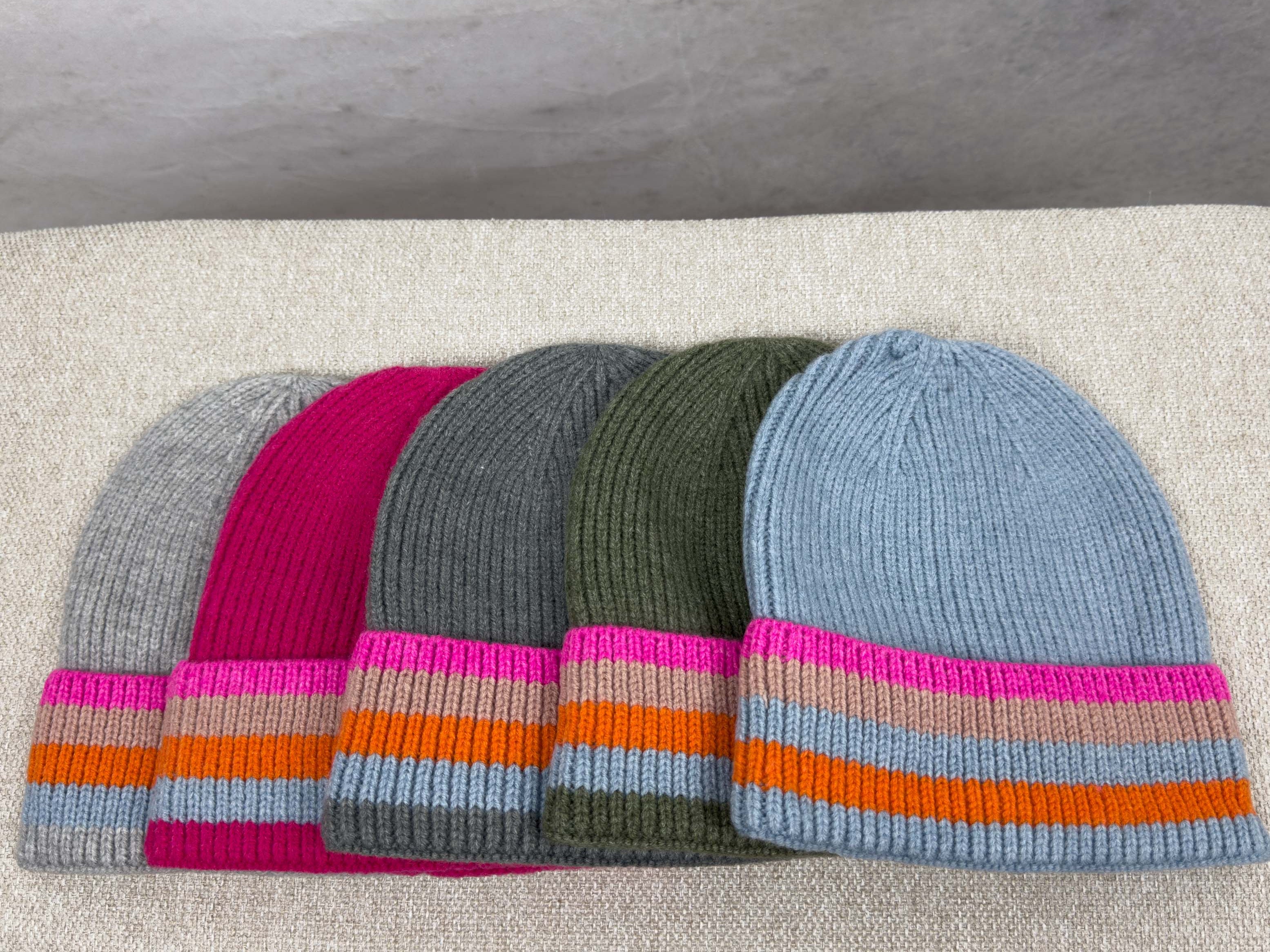 Fuenf gerippte Strickmuetzen in Grau, Pink, Dunkelgrau, Olivgruen und Hellblau mit breitem Umschlag und Streifen in Pink, Beige, Orange und Hellblau