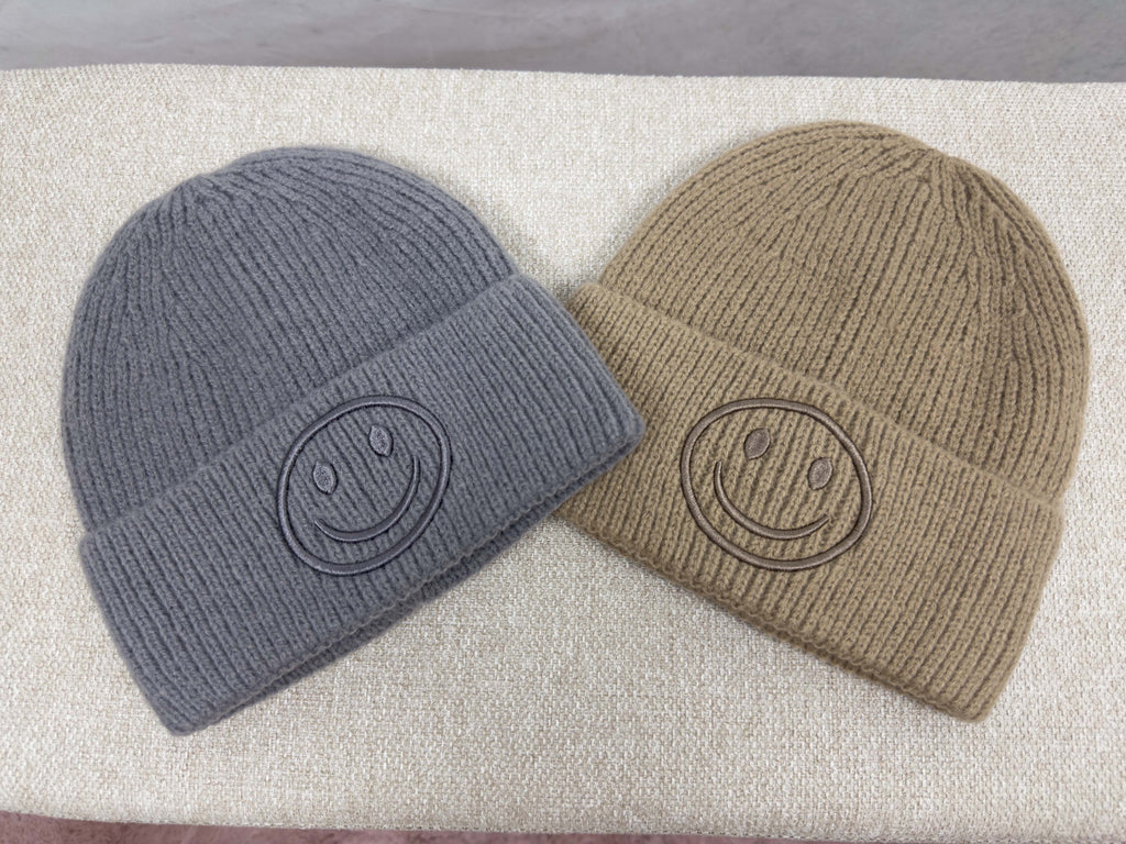 Zwei gerippte Strickmuetzen in Grau und Beige mit breitem Umschlag und tonalem Smiley Stick auf der Vorderseite