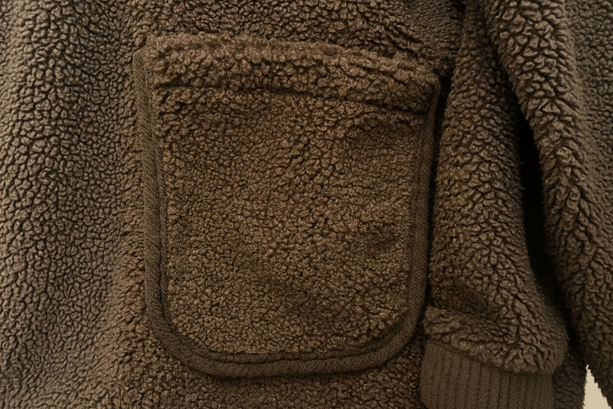 Detailansicht der aufgesetzten Tasche der Teddyjacke „Rosie“ mit Kontrastkante in Braun