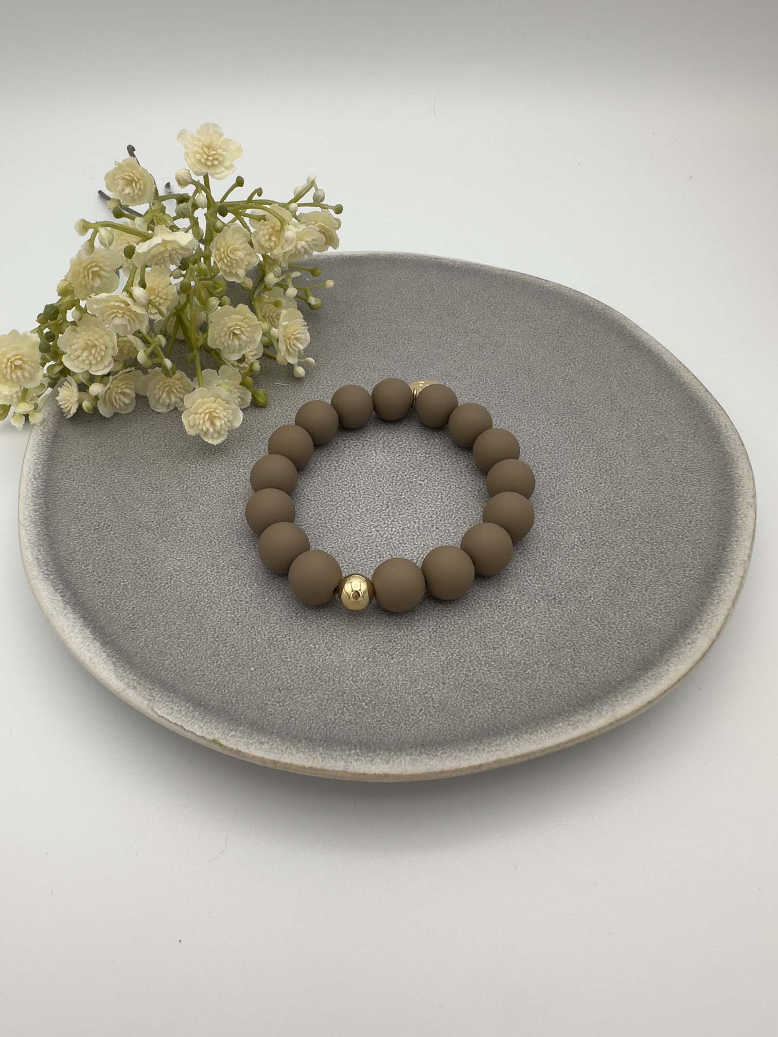 Elastisches Armband mit matten taupefarbenen Perlen und einer goldenen Kugel