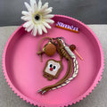 Ein bunter Schluesselanhaenger mit mehreren Anhaengern darunter ein Burger, ein Lolli und eine lachende Toast Figur mit roter Nase sowie zwei geflochtenen Kordeln in Braun und Weiss
