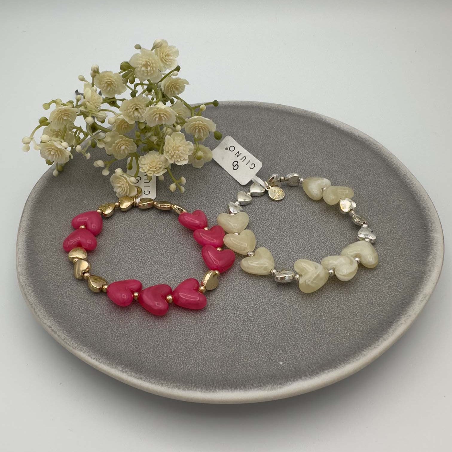 Set aus zwei Herzarmbändern in Pink mit Gold und Creme mit Silber.